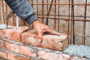 Man putting a brick with concrete