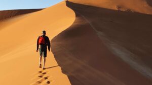 homme dans le désert avec un sac à dos rouge